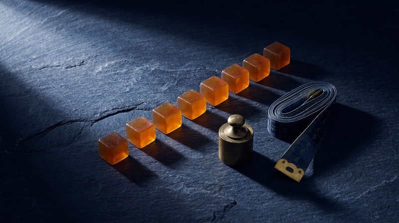 Amber gummies arranged in an ascending row beside a brass weight — CBD gummy dosage by body weight